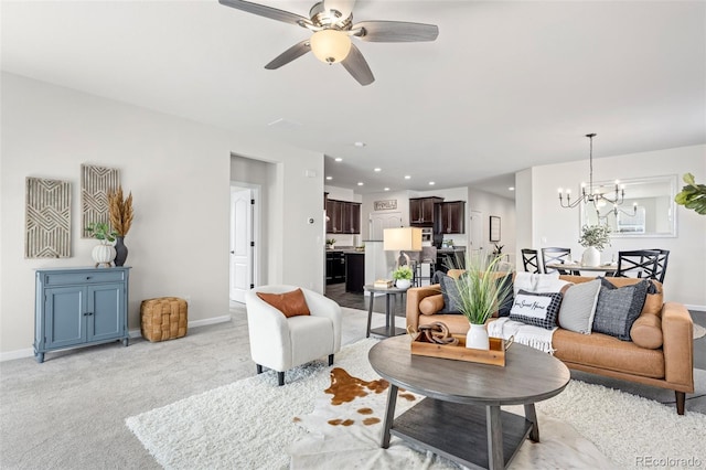 living area featuring light carpet, ceiling fan with notable chandelier, baseboards, and recessed lighting