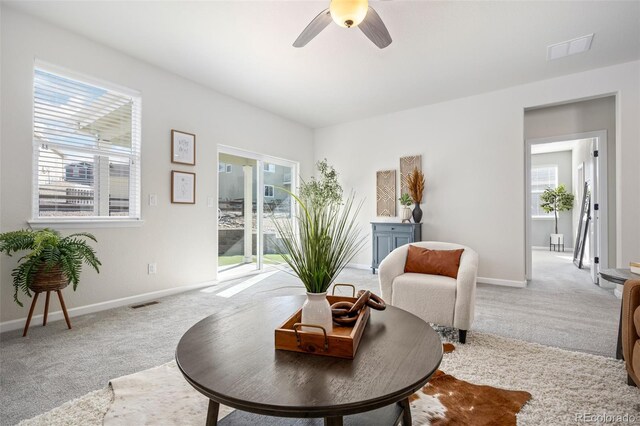 sitting room featuring visible vents, ceiling fan, light carpet, and baseboards