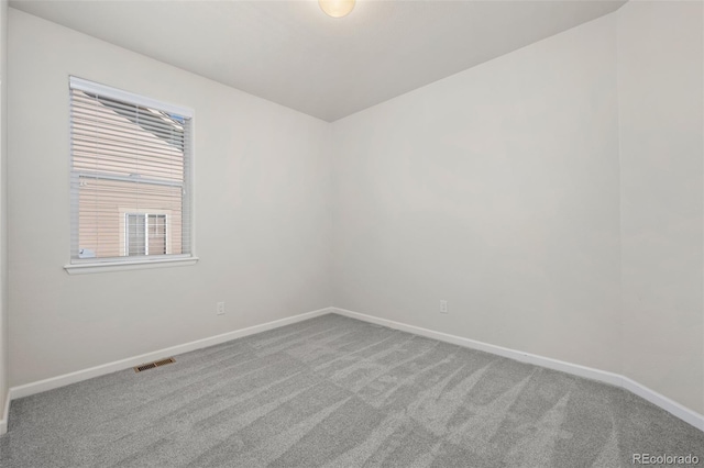 carpeted spare room featuring visible vents and baseboards