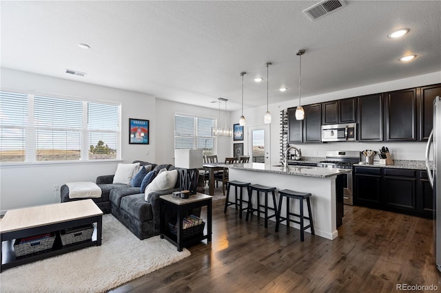 living area featuring dark wood-type flooring, visible vents, recessed lighting, and a textured ceiling