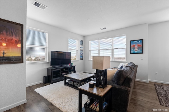 living room featuring visible vents, baseboards, and wood finished floors