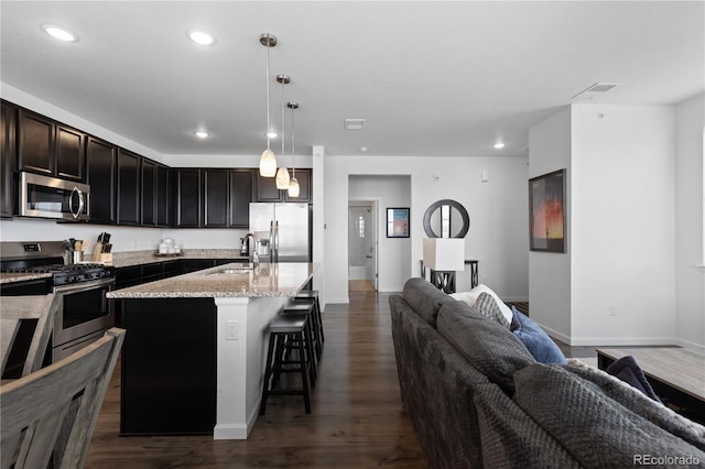 kitchen featuring a kitchen bar, appliances with stainless steel finishes, dark wood-style flooring, a sink, and open floor plan