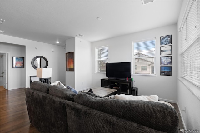 living area featuring dark wood-type flooring, visible vents, and baseboards