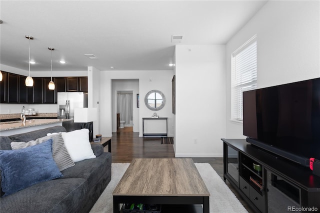 living room featuring visible vents, baseboards, recessed lighting, and dark wood finished floors
