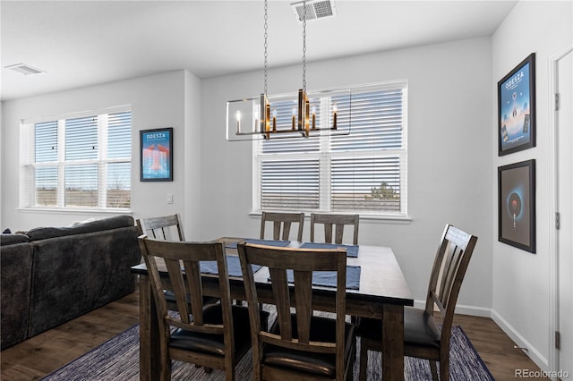 dining space featuring a notable chandelier, dark wood finished floors, visible vents, and a wealth of natural light