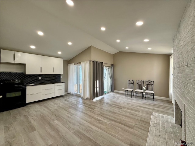 kitchen featuring lofted ceiling, a brick fireplace, black / electric stove, white cabinetry, and light hardwood / wood-style flooring