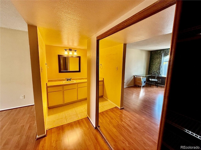 hall featuring sink, wood-type flooring, and a textured ceiling