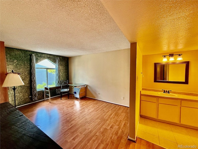 interior space with a textured ceiling, light hardwood / wood-style flooring, and sink