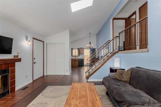 living area with a tiled fireplace, dark wood-style floors, stairs, and visible vents