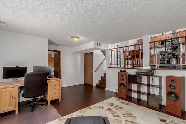 office area featuring baseboards, wood finished floors, visible vents, and a textured ceiling