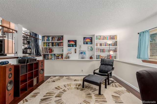 living area with wood finished floors, baseboards, and a textured ceiling