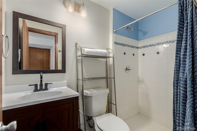 full bathroom featuring vanity, toilet, a textured wall, and a tile shower