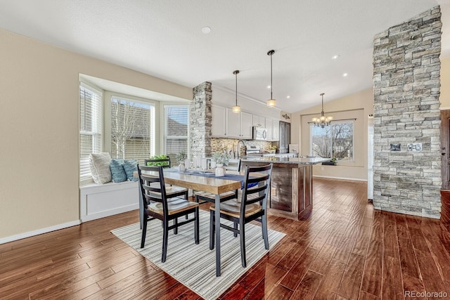 dining room featuring a healthy amount of sunlight, vaulted ceiling, and dark wood-type flooring