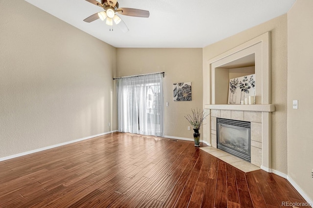 unfurnished living room featuring a tile fireplace, ceiling fan, wood-type flooring, and vaulted ceiling