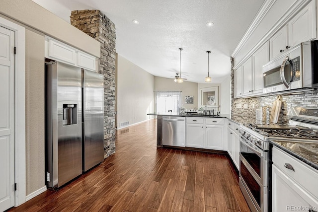 kitchen featuring appliances with stainless steel finishes, backsplash, decorative light fixtures, white cabinetry, and lofted ceiling