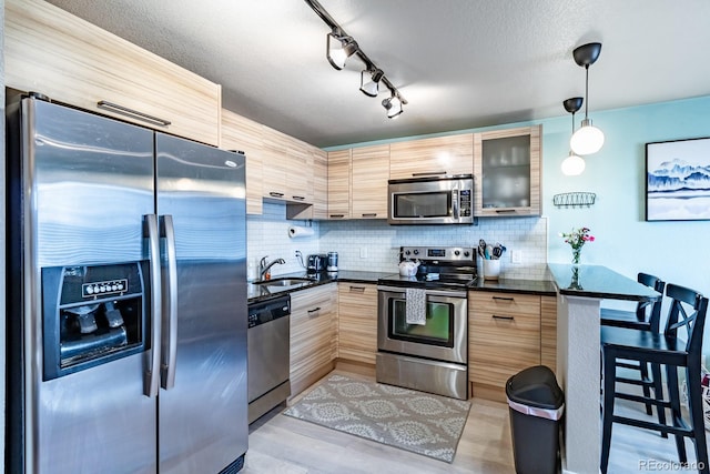 kitchen featuring sink, a breakfast bar, appliances with stainless steel finishes, decorative backsplash, and decorative light fixtures