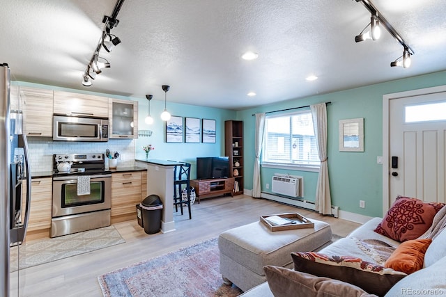 living room featuring a wall mounted air conditioner, light hardwood / wood-style flooring, and a textured ceiling