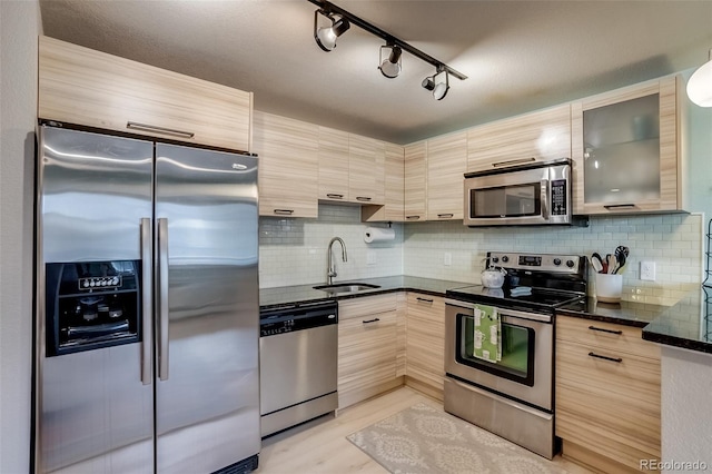 kitchen with appliances with stainless steel finishes, decorative backsplash, a sink, and light brown cabinetry