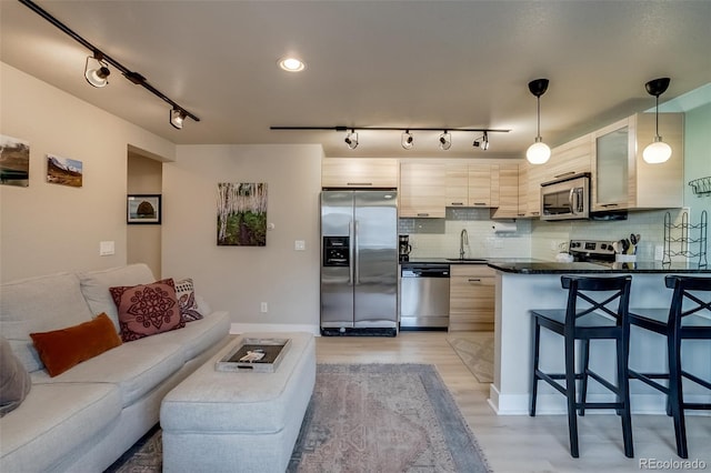 kitchen featuring appliances with stainless steel finishes, dark countertops, a sink, and tasteful backsplash