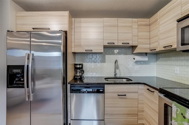 kitchen featuring appliances with stainless steel finishes, dark stone countertops, a sink, and decorative backsplash