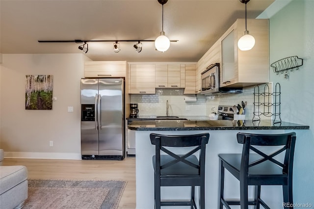 kitchen featuring a peninsula, decorative backsplash, stainless steel appliances, and a sink