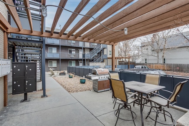 view of patio featuring outdoor dining area, fence, and mail area