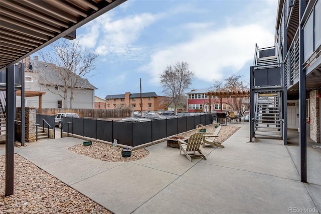 view of patio featuring an outdoor fire pit, a fenced backyard, a residential view, and stairs