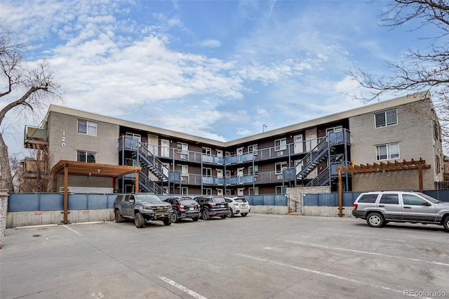 view of building exterior featuring uncovered parking and fence