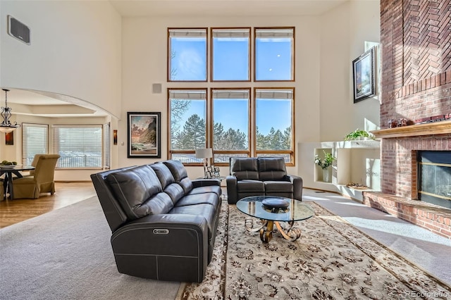 carpeted living room featuring a towering ceiling and a fireplace