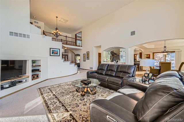 carpeted living room with built in shelves, a high ceiling, and a notable chandelier