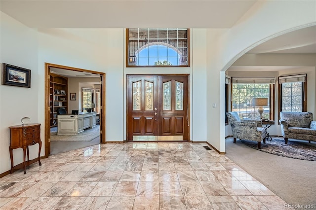 entryway with light carpet and a high ceiling