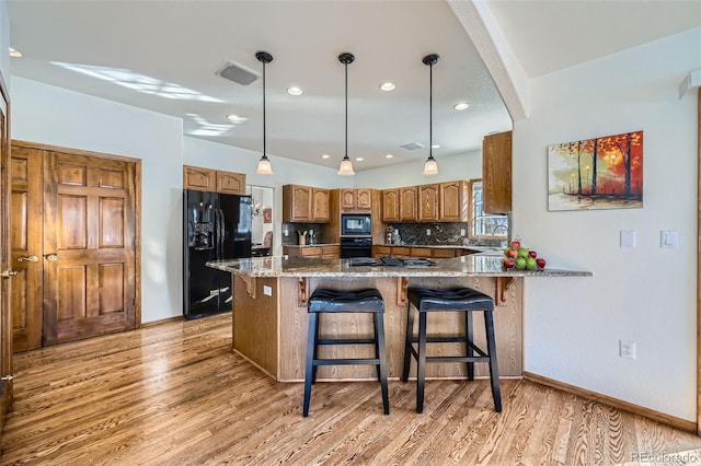 kitchen with stone countertops, sink, light wood-type flooring, and black appliances