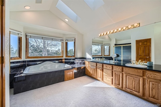 bathroom featuring vanity, a relaxing tiled tub, and lofted ceiling with skylight