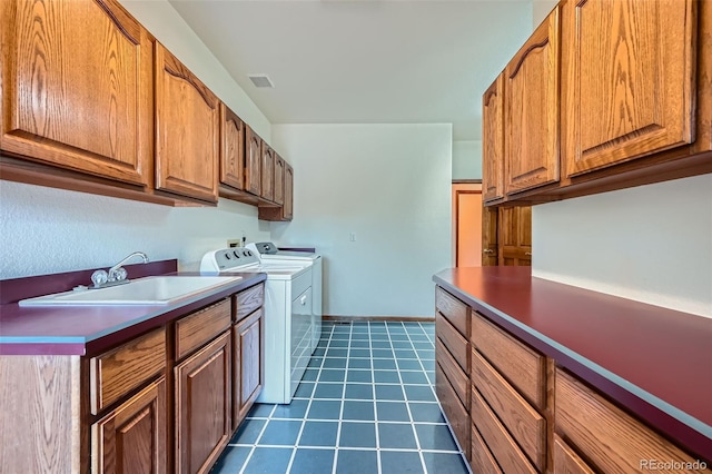 laundry area with cabinets, washing machine and dryer, sink, and dark tile patterned flooring