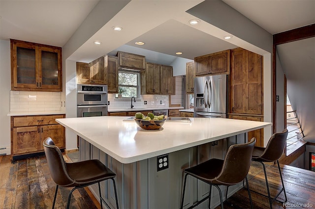 28051 Camel Heights Cir, Evergreen, CO 80439 - kitchen featuring stainless steel appliances, dark wood-style flooring, a kitchen bar, backsplash, and recessed lighting