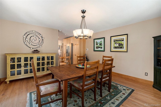dining room with a chandelier, light wood finished floors, and baseboards