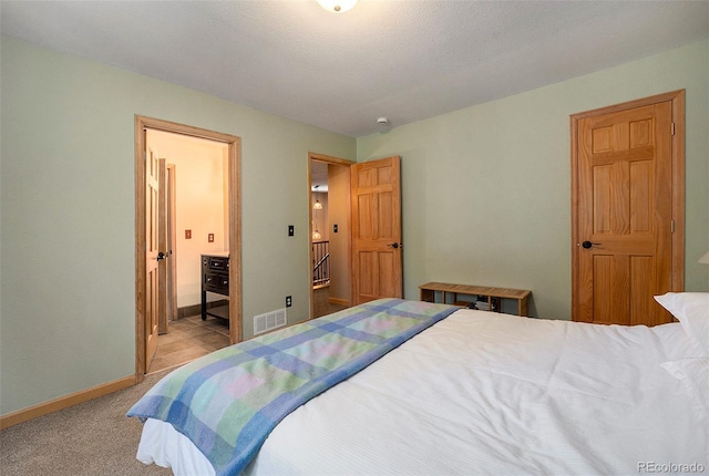carpeted bedroom with baseboards and ensuite bath