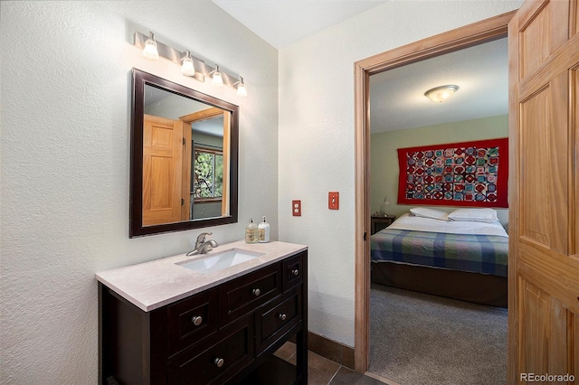 bathroom featuring vanity, a textured wall, and ensuite bathroom