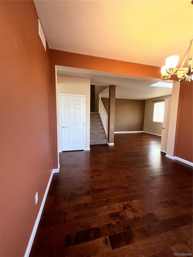 corridor with dark hardwood / wood-style floors and an inviting chandelier