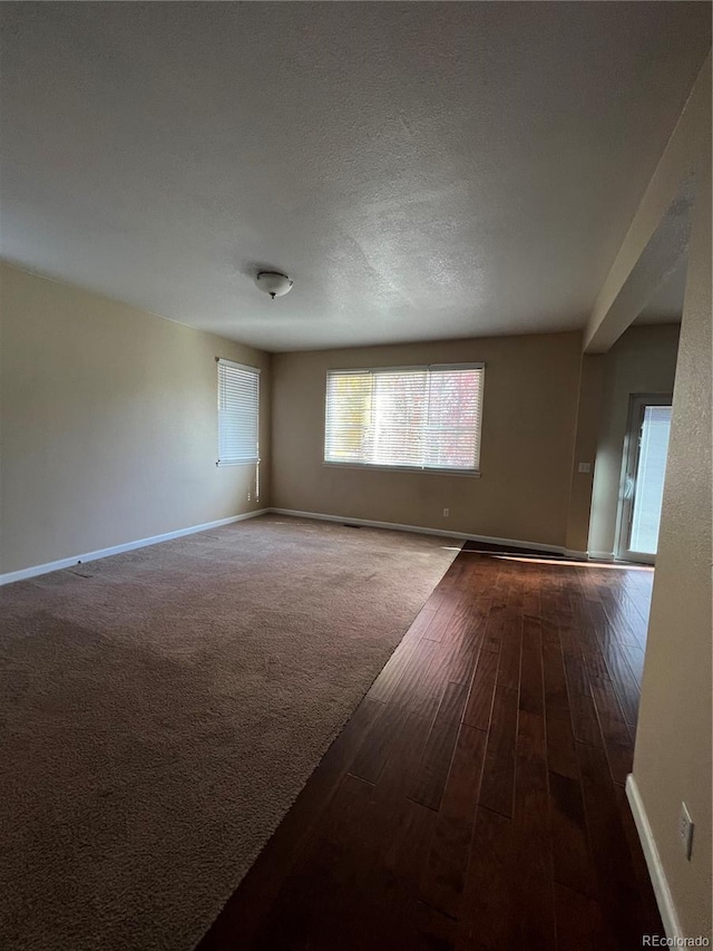 empty room featuring a textured ceiling and dark hardwood / wood-style flooring