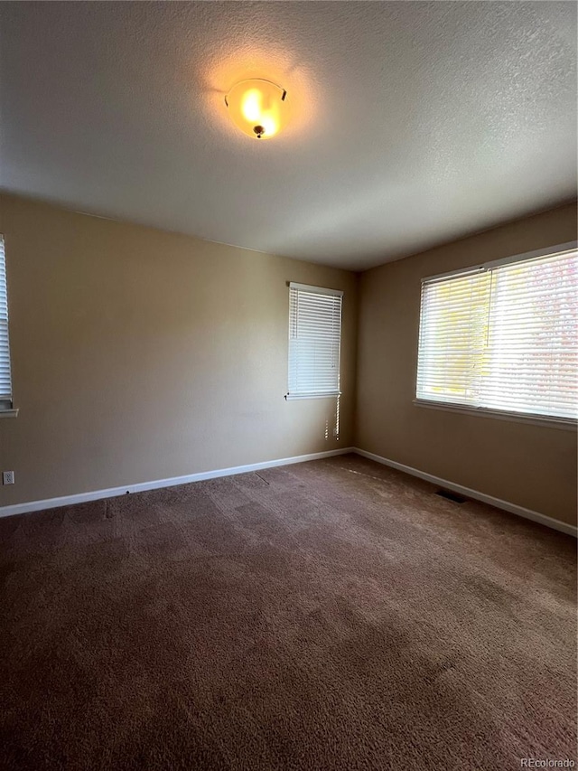 empty room with carpet floors and a textured ceiling