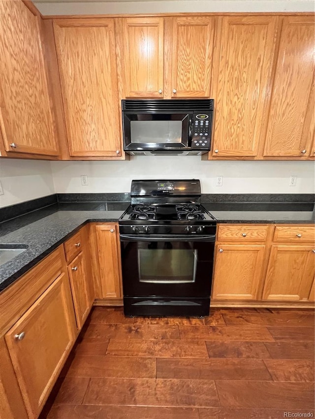 kitchen featuring dark stone counters, dark hardwood / wood-style floors, and black appliances