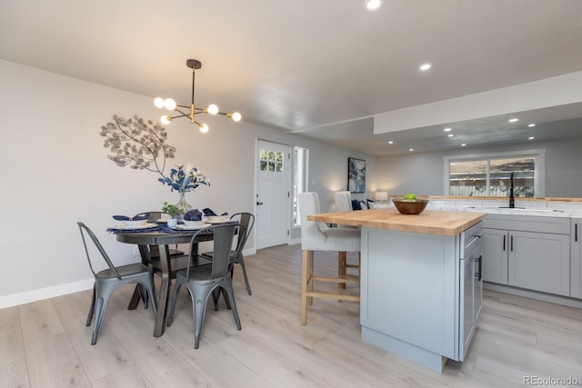 kitchen featuring sink, gray cabinets, hanging light fixtures, a kitchen island, and wood counters