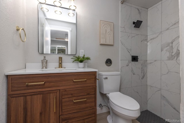 bathroom with vanity, toilet, and a tile shower