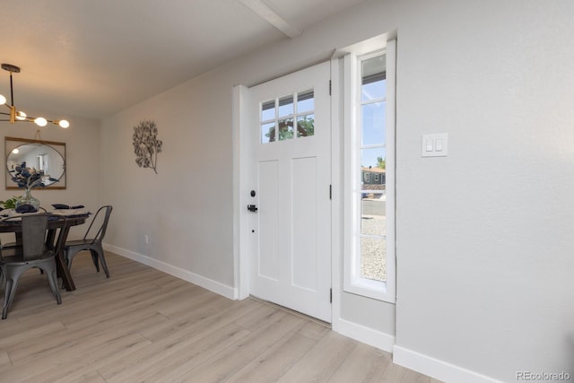 entrance foyer with a notable chandelier, light hardwood / wood-style floors, and a healthy amount of sunlight