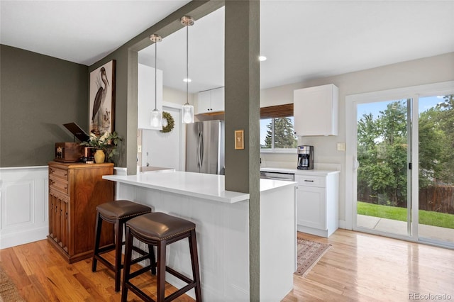 12705 W Chenango Ave, Morrison, CO 80465 - kitchen with stainless steel appliances, light wood-style floors, white cabinets, light countertops, and a kitchen breakfast bar