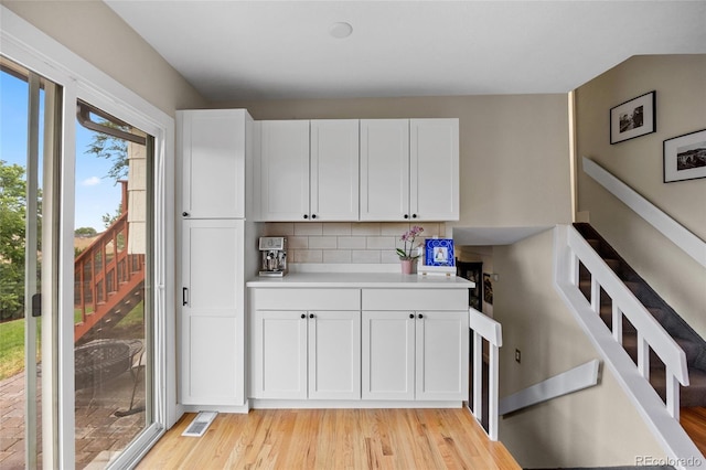 12705 W Chenango Ave, Morrison, CO 80465 - kitchen featuring light wood-type flooring, white cabinets, light countertops, and tasteful backsplash