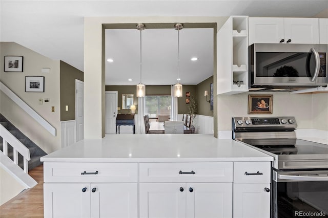 12705 W Chenango Ave, Morrison, CO 80465 - kitchen with stainless steel appliances, light countertops, white cabinets, light wood-style flooring, and a peninsula