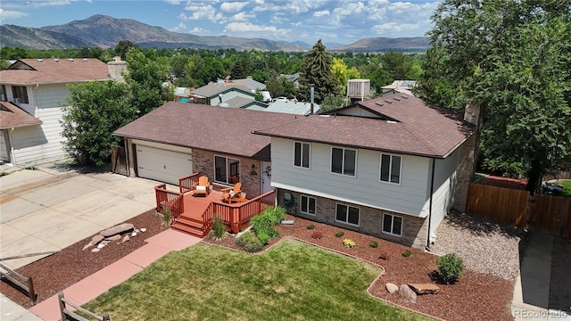 12705 W Chenango Ave, Morrison, CO 80465 - view of front facade with concrete driveway, a deck with mountain view, an attached garage, roof with shingles, and a chimney