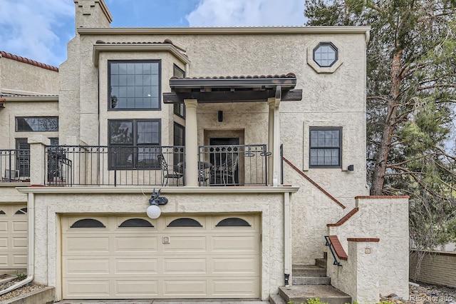 multi unit property featuring a balcony, stucco siding, an attached garage, and a chimney